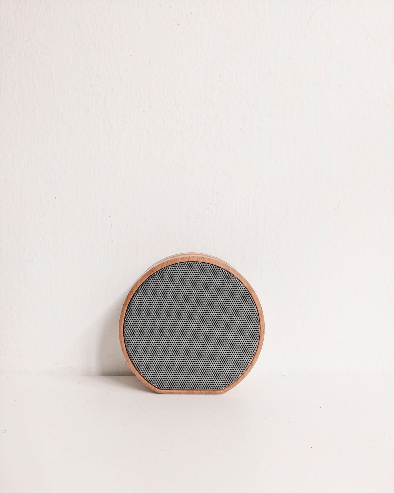 Round wood-framed speaker against a pale wall