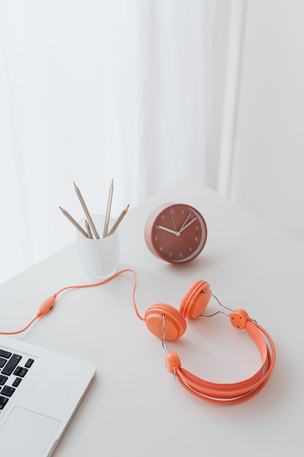 Headphones and a warm clock on a white desk