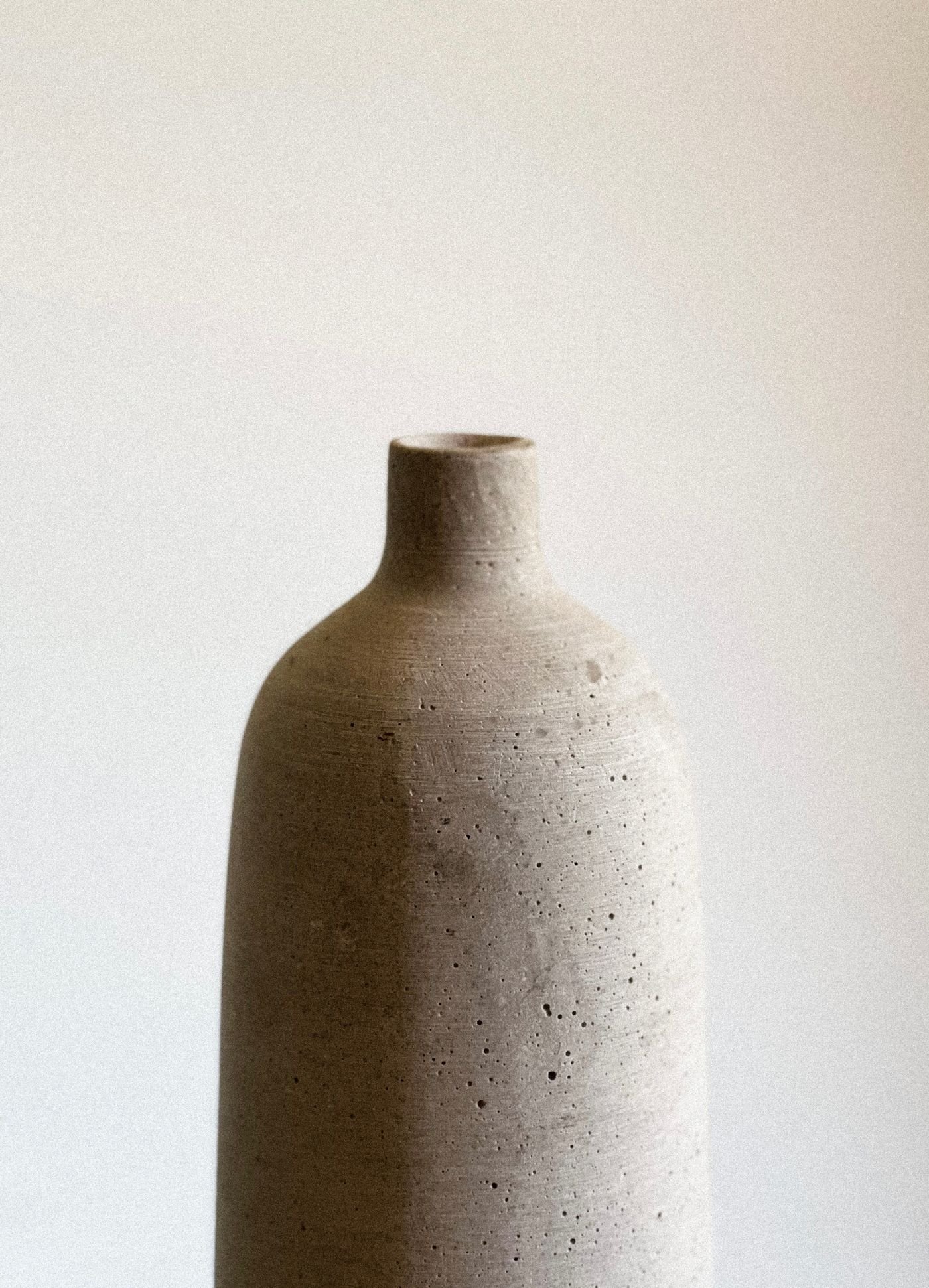 Single textured grey clay vase against a soft background