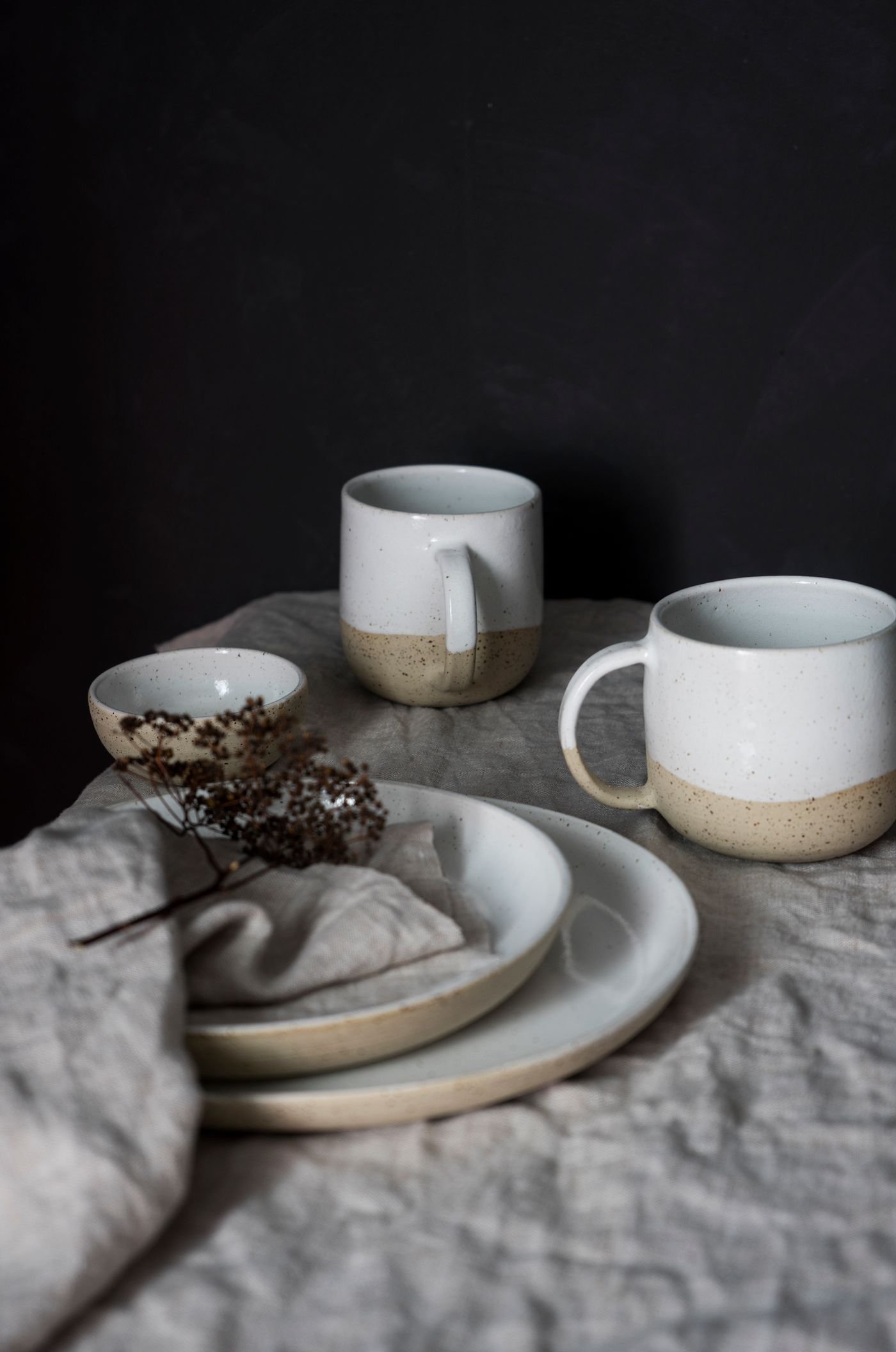 Neutral ceramic cups and plates arranged on linen