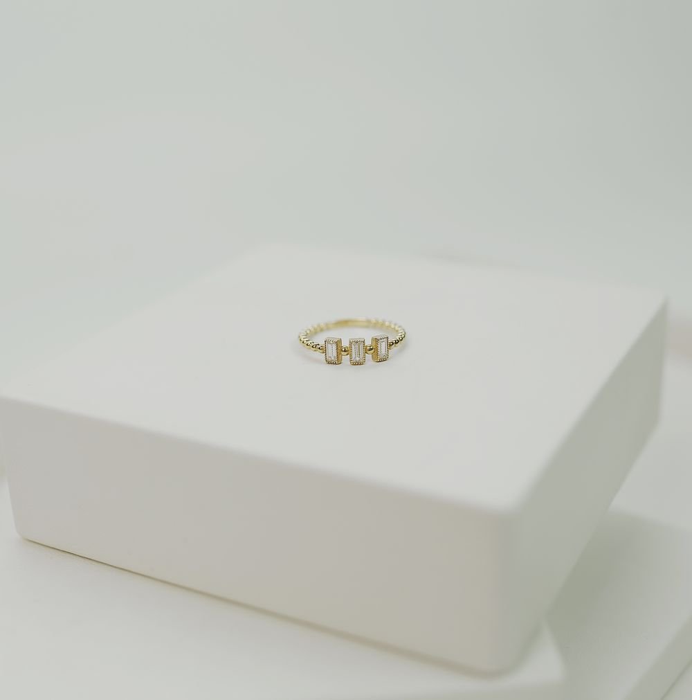 Simple gold ring displayed against a soft neutral background