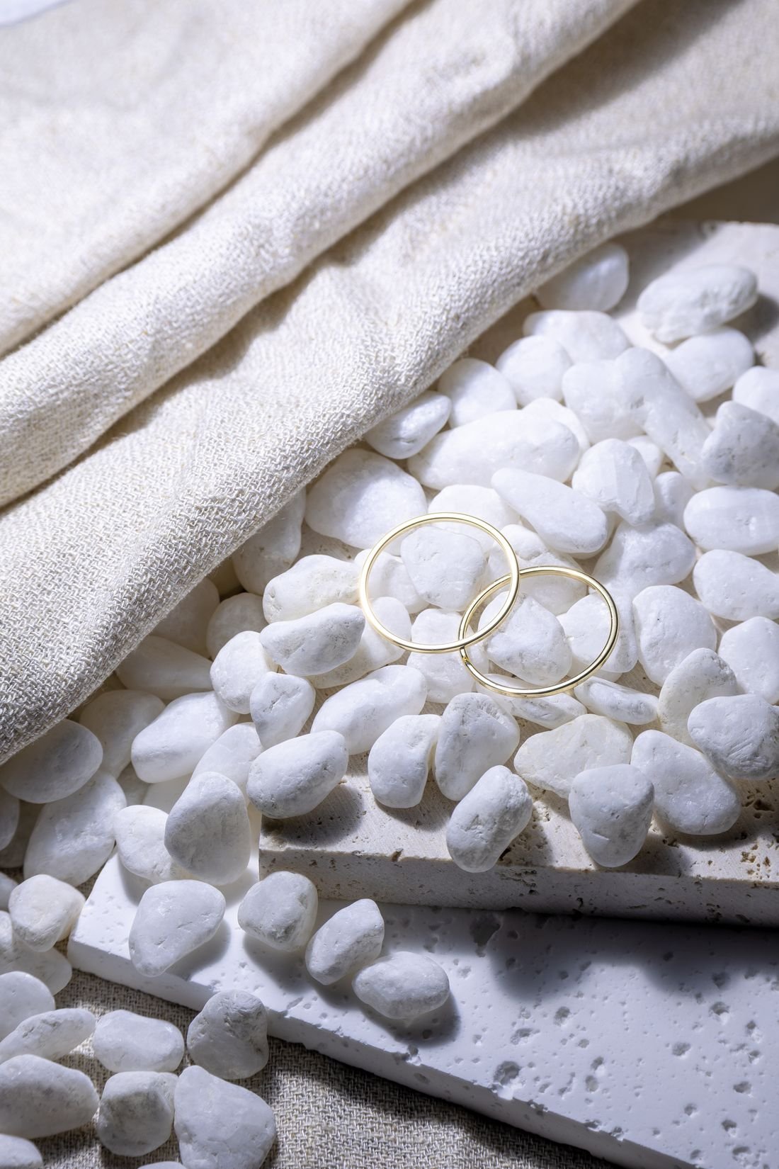 Gold rings arranged among pale stone pebbles