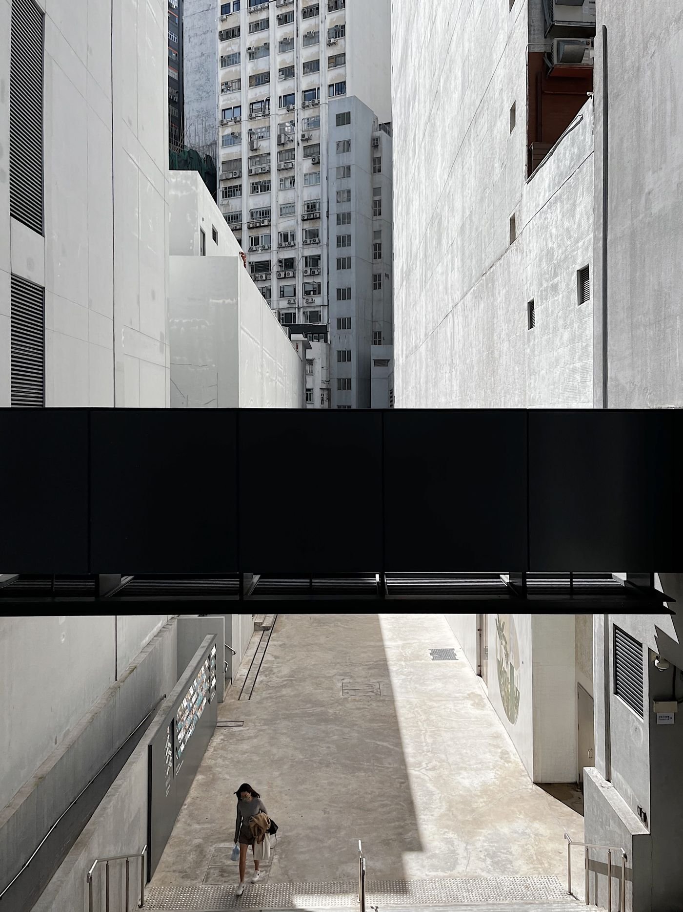 Sunlit urban alley framed by modern buildings and a dark walkway
