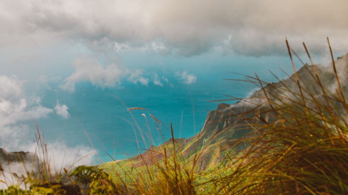 Clouds drifting above a green coastal ridge and blue sea