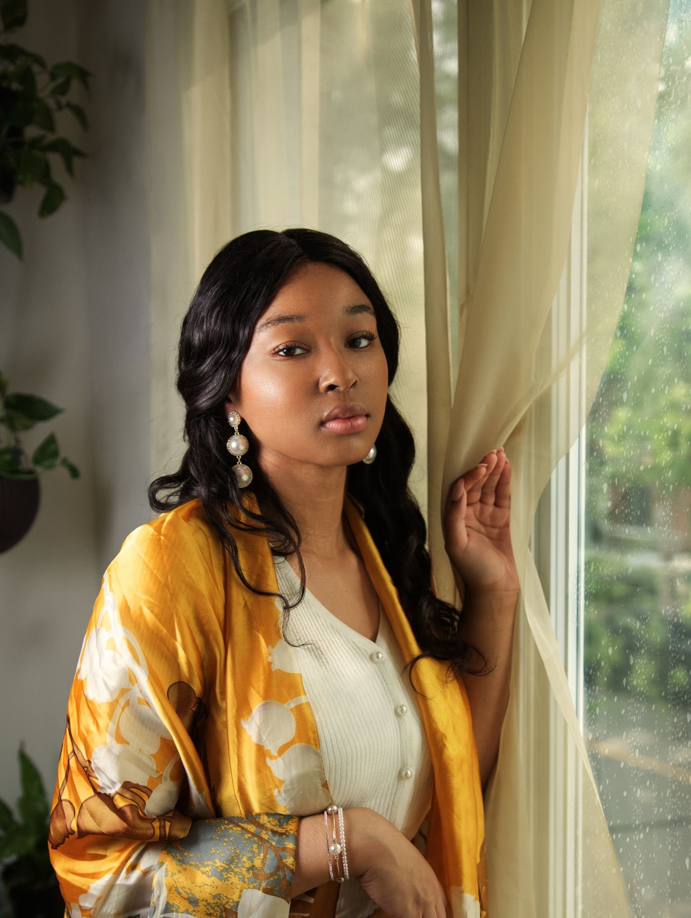 Portrait of a woman in golden fabric by a window, photographed by Tisha Vassel