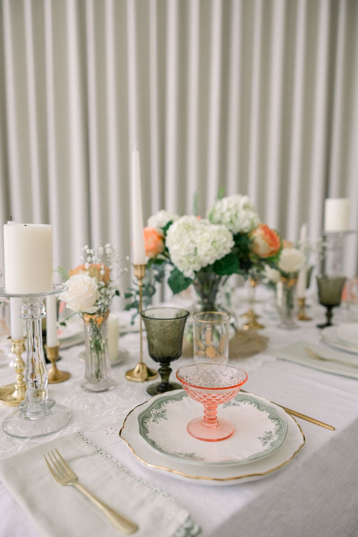 An intimate wedding place setting with flowers, candles, and vintage glassware