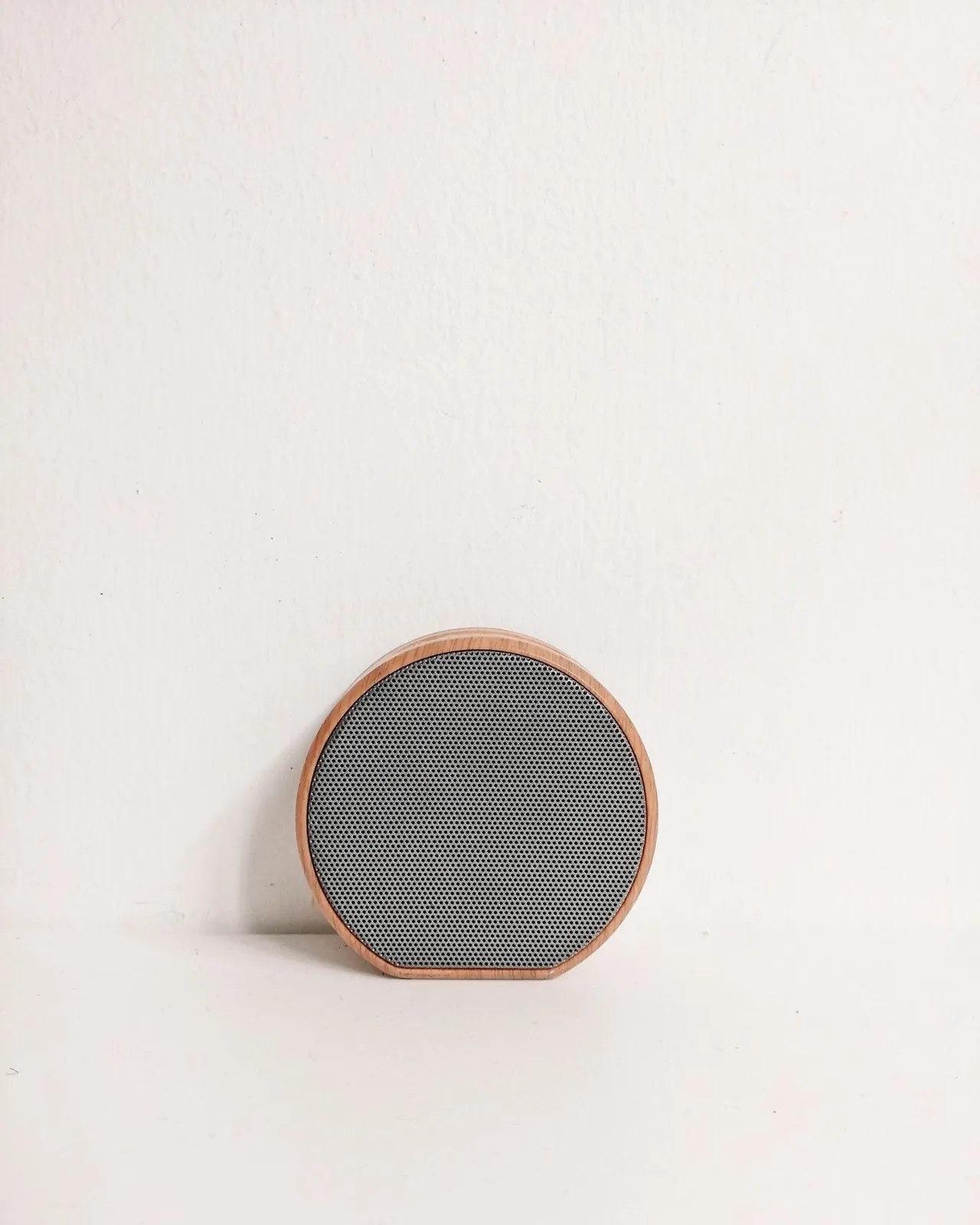 Orbit speaker in cork and grey fabric, standing on a pale surface