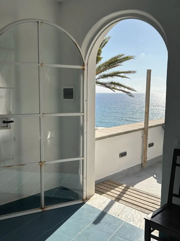 Arched glass door opening onto a terrace above the sea