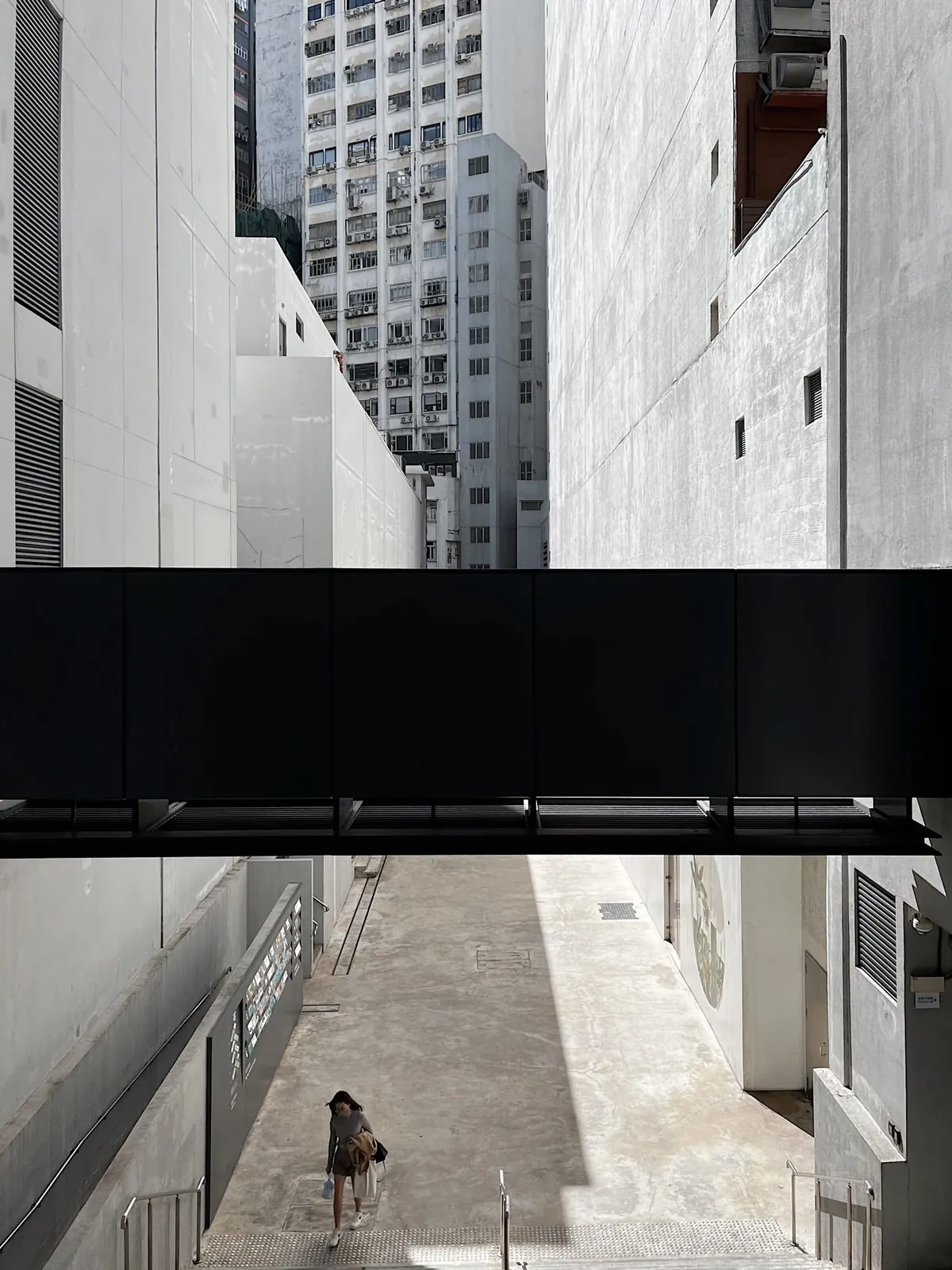 Sunlit alley between modern concrete buildings