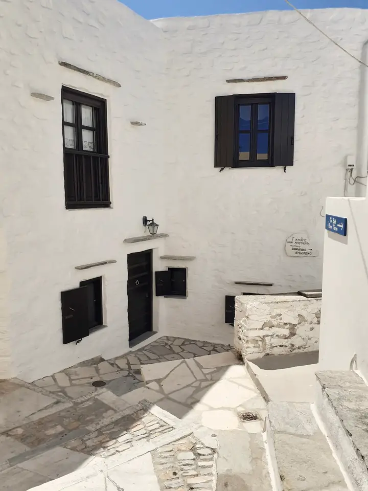 Whitewashed courtyard house with dark shutters and stone paving