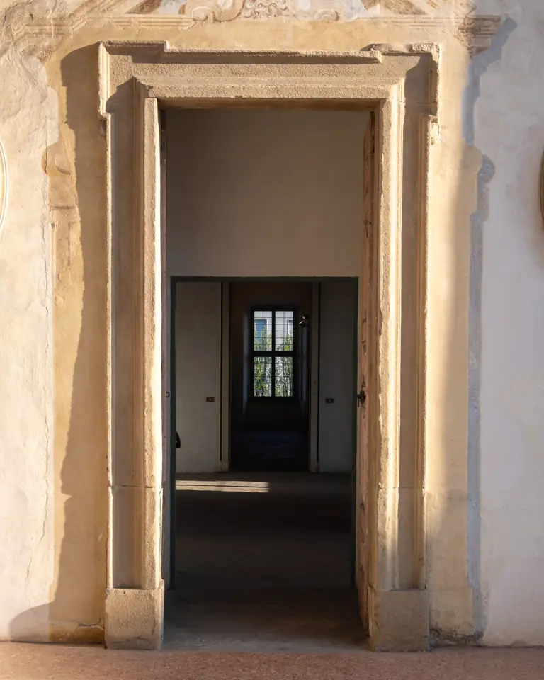 Carved limestone doorway opening onto a row of sunlit rooms