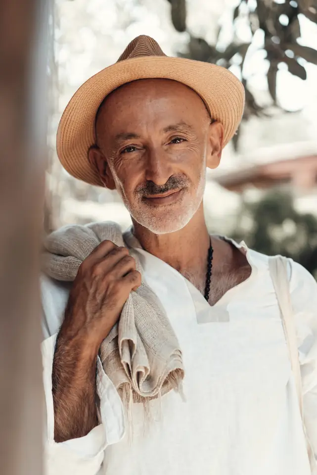 Smiling man in a straw hat and white shirt with a towel over his shoulder