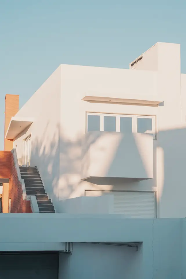Geometric white modern house with an outside stair against a pale sky